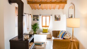A cozy living room with a fireplace, wooden ceiling beams, a sofa, a table, and a lamp. - Home set in Olive Grove With Stunning Views (Mondavio)