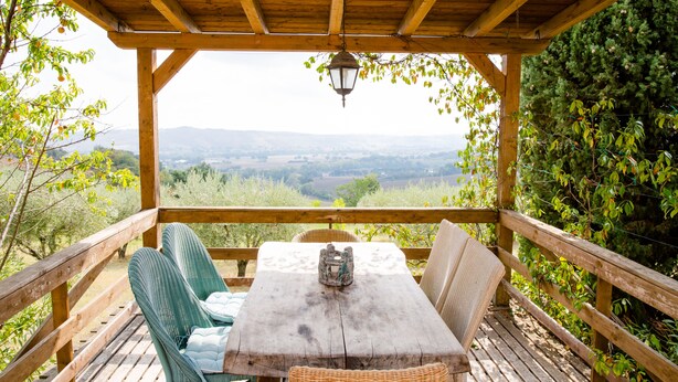 A wooden deck with a table and chairs, overlooking a scenic valley. - Home set in Olive Grove With Stunning Views (Mondavio)