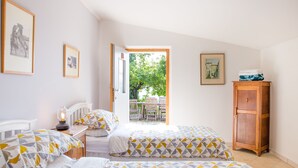 A bedroom with two beds, a wooden cabinet, and a window leading to an outdoor area. - Home set in Olive Grove With Stunning Views (Mondavio)