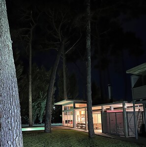 A modern outdoor structure with glass walls, surrounded by trees, and illuminated by artificial lighting. - Beautiful architecturally designed home, close to everything (Punta del Este)