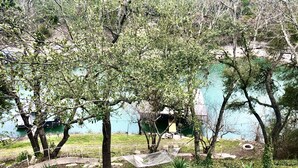 A serene outdoor area with trees, a hammock, and a small water body. - Spacious lakefront home with dock - perfect for a group getaway (Lago Vista)