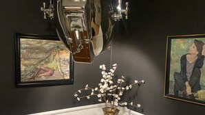 A dining area with a round table, a chair, a vase with flowers, and two framed artworks on the wall. - Family Apt ❤️ underground parking❤️smoking balcony (Sector 2)