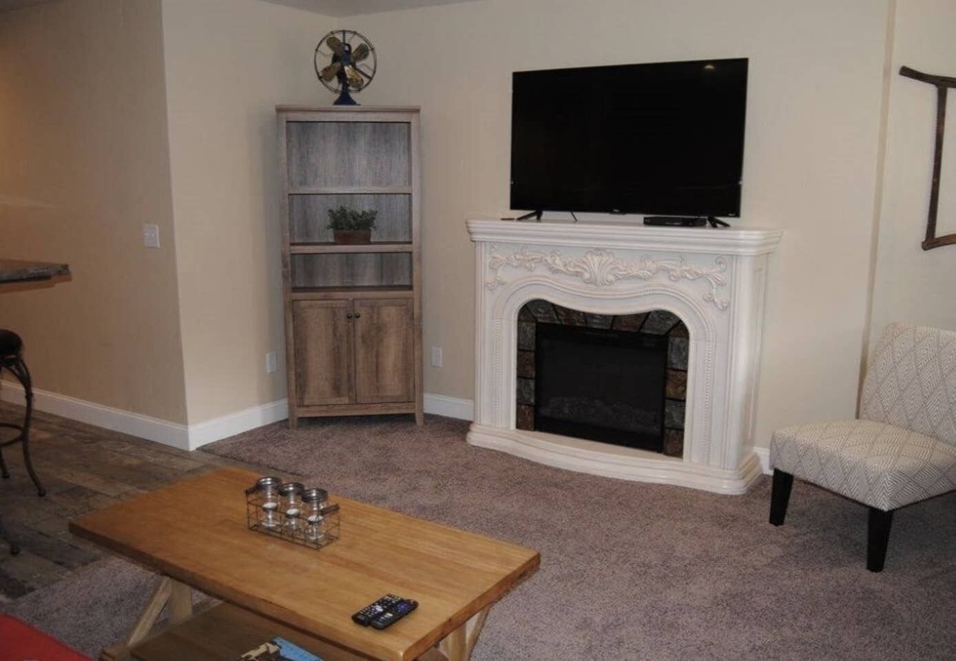 A living room with a fireplace, a television, a wooden cabinet, and a chair.
