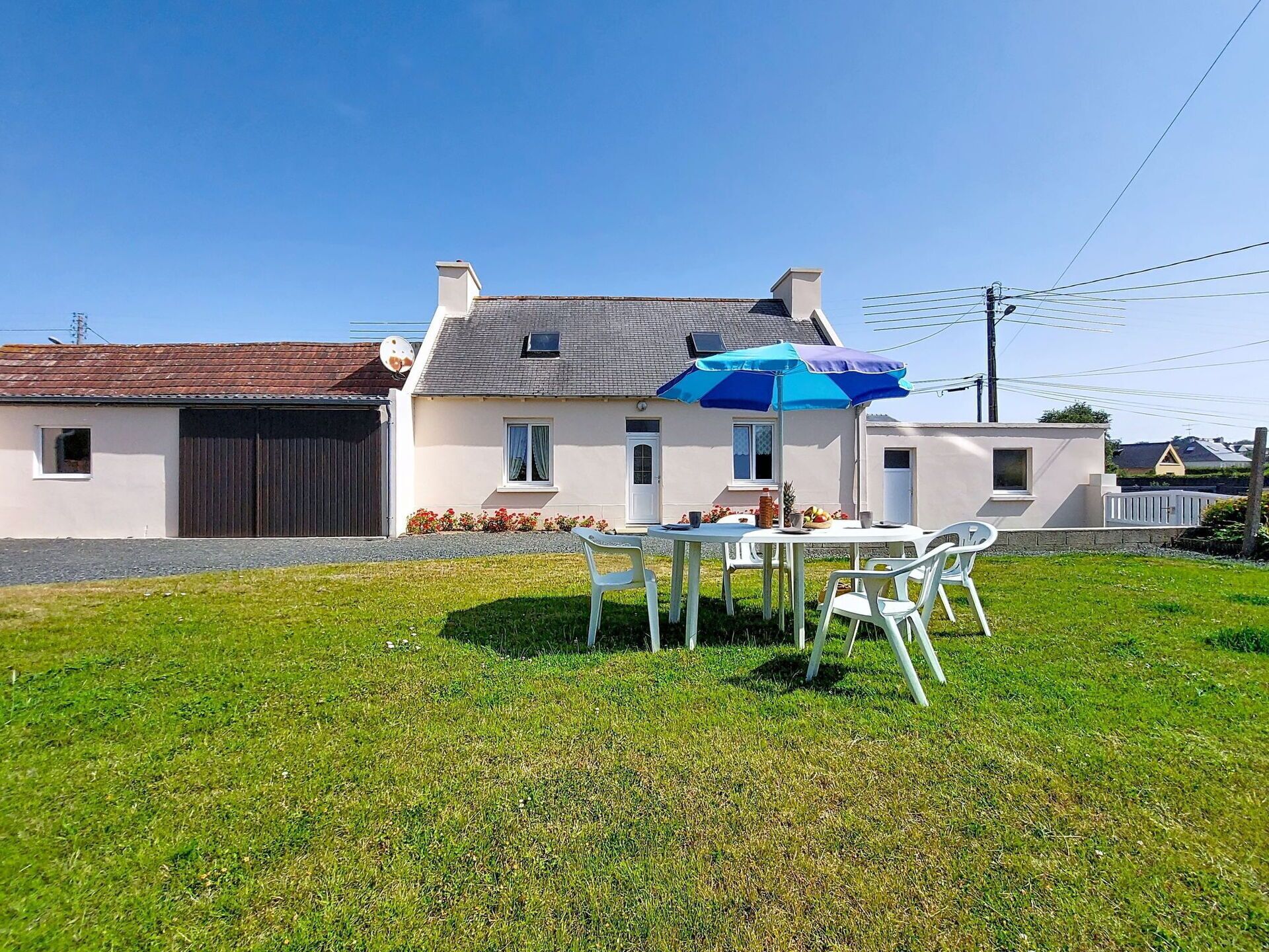 A house with a white exterior, a garage, and a small patio with a table and chairs.