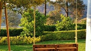 A wooden swing suspended by ropes in a lush garden with neatly trimmed hedges and trees in the background. - Cabaña La Rayuela Valle de Bravo (Valle de Bravo)