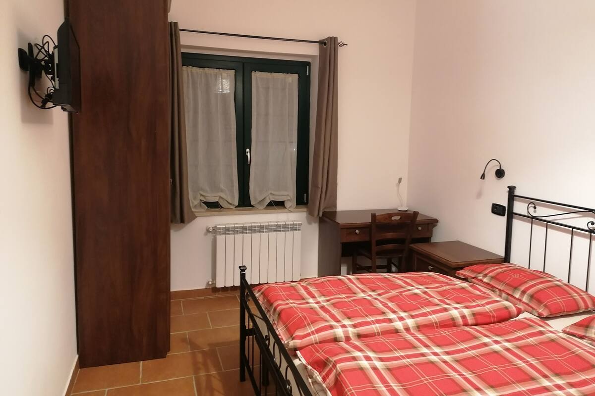 A bedroom with a bed, a desk, and a chair.