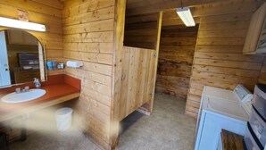 A wooden cabin bathroom with a sink, mirror, and wooden toilet stall. - Bear Cabin in the Heart of Moose Country Alaska! (Ninilchik)