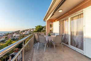 Uma varanda com mesa e cadeiras, com vista para uma cidade costeira.