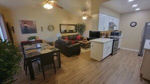 Un salon moderne comprenant un coin repas, une cuisine et un ventilateur de plafond.