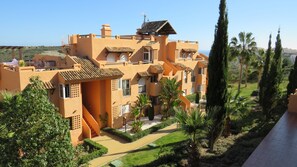 A modern building with multiple balconies and a garden area.