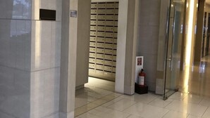 Moderni aula, jossa on laatoitettu lattia, lasihissi ja palosammutin.