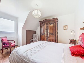 Un dormitorio con una cama grande, un armario de madera, una silla y una araña.