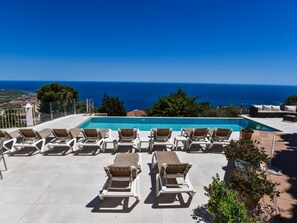 Zona de piscina al terrat amb gandules i vista al mar.