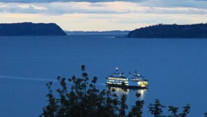 A cruise ship on a calm body of water with distant landmasses and a cloudy sky.