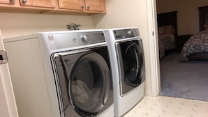 A laundry room with two front-loading washing machines and a wooden cabinet above them.