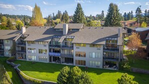 A multi-story residential building with balconies, large windows, and a well-maintained lawn.