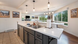 A spacious kitchen with a large island, modern pendant lights, and artwork on the walls.