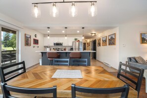 Moderni keittiö, jossa on valkoiset kaapit, keskellä oleva keittiösaareke ja riippuvalaisimet.