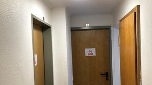 A narrow hallway with wooden doors on either side and a ceiling light. - Hotel Holthausen (Uebach-Palenberg)