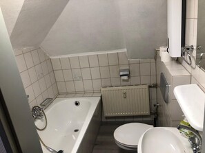 A small bathroom with a bathtub, toilet, and sink. - Hotel Holthausen (Uebach-Palenberg)