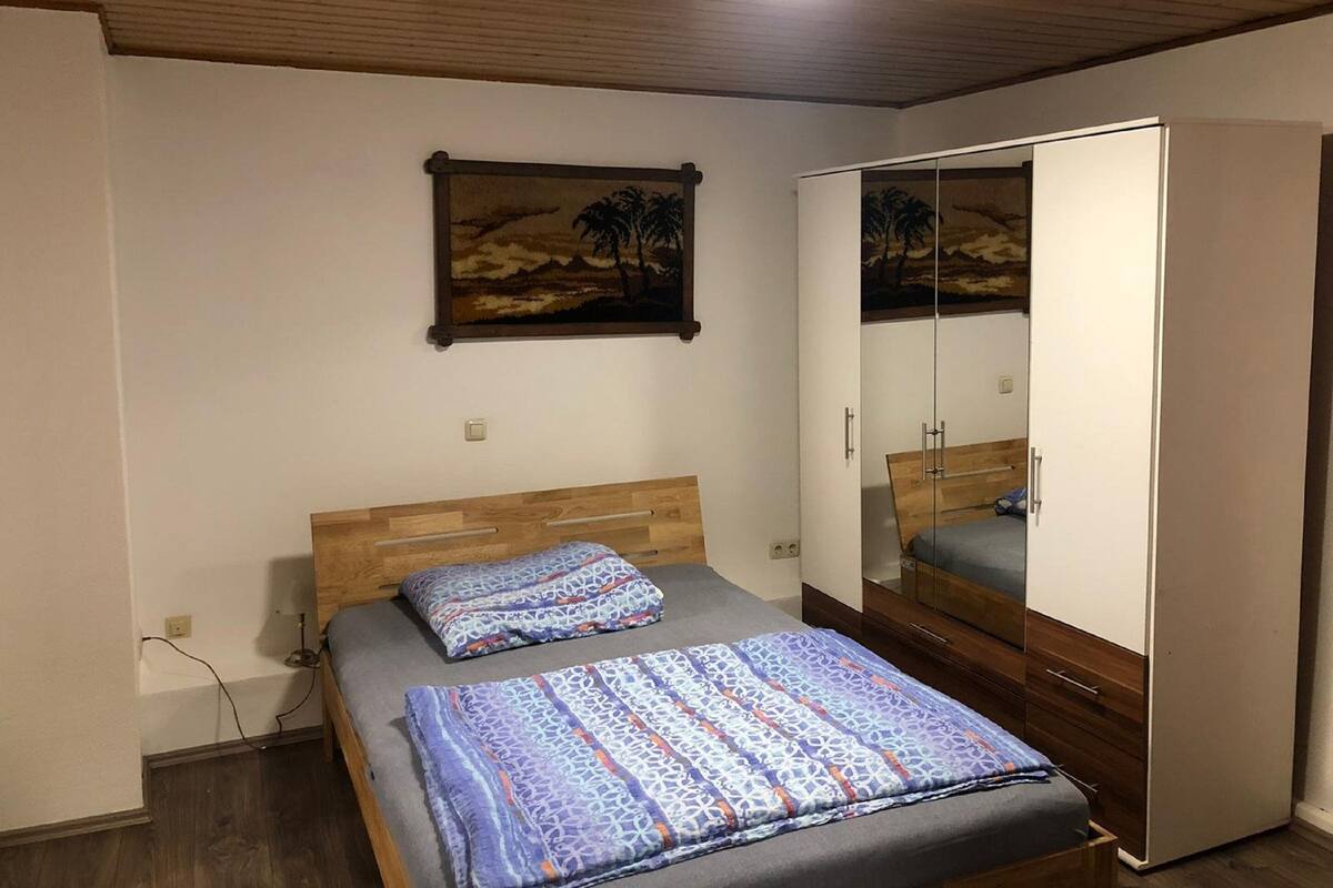 Ein Schlafzimmer mit einem hölzernen Bett, einem Kleiderschrank und einem Gemälde an der Wand.