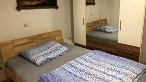 A bedroom with two beds, a wardrobe, and a painting on the wall. - Hotel Holthausen (Uebach-Palenberg)