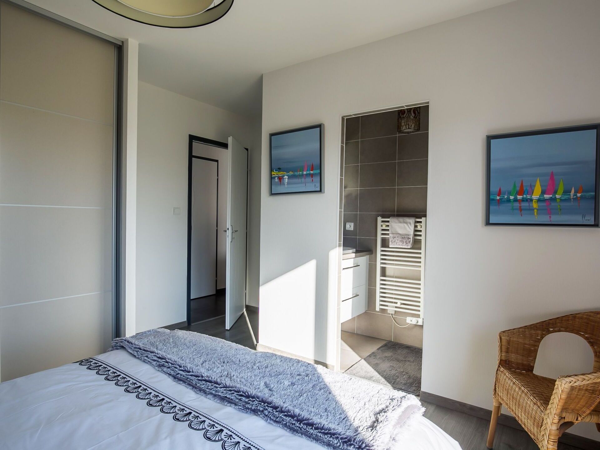 A bedroom with a bed, a chair, a radiator, and artwork on the wall.