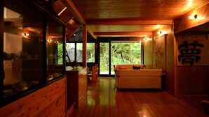 A wooden interior with a sofa, wooden cabinets, and large windows. - Shikinosato HANAMURA (Minamioguni)
