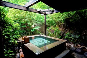 A hot tub in a lush garden with a wooden pergola overhead. - Shikinosato HANAMURA (Minamioguni)