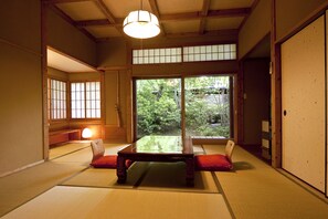 Una habitación japonesa tradicional con suelo de tatami, una mesa de madera baja y puertas correderas.