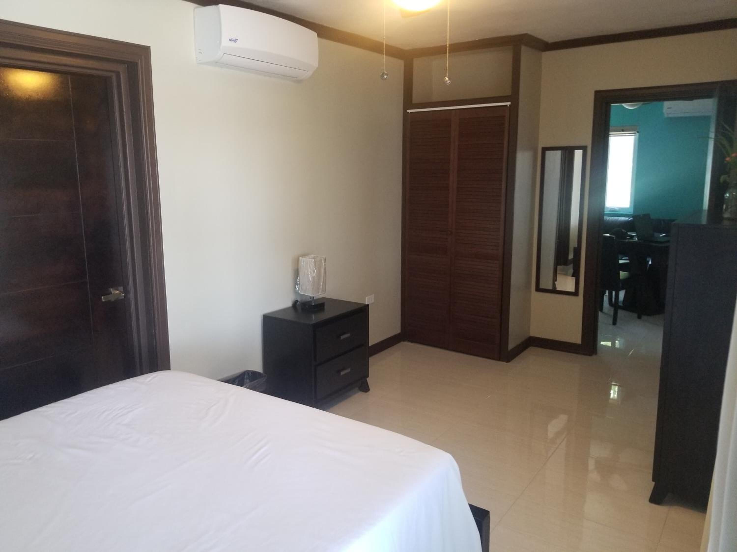 Een slaapkamer met een bed, een dressoir, een kledingkast en een airconditioning.