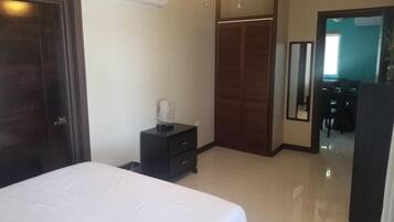A bedroom with a bed, a dresser, a wardrobe, and an air conditioning unit.