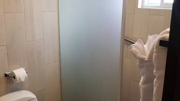 A bathroom with a toilet, a shower stall, and a towel rack.
