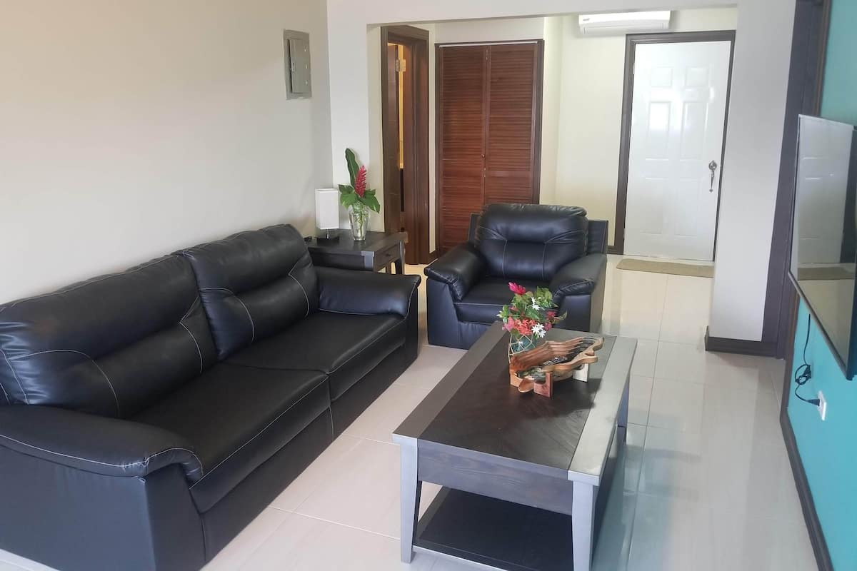 A living room with a black leather sofa, a matching armchair, and a coffee table with a vase of flowers.