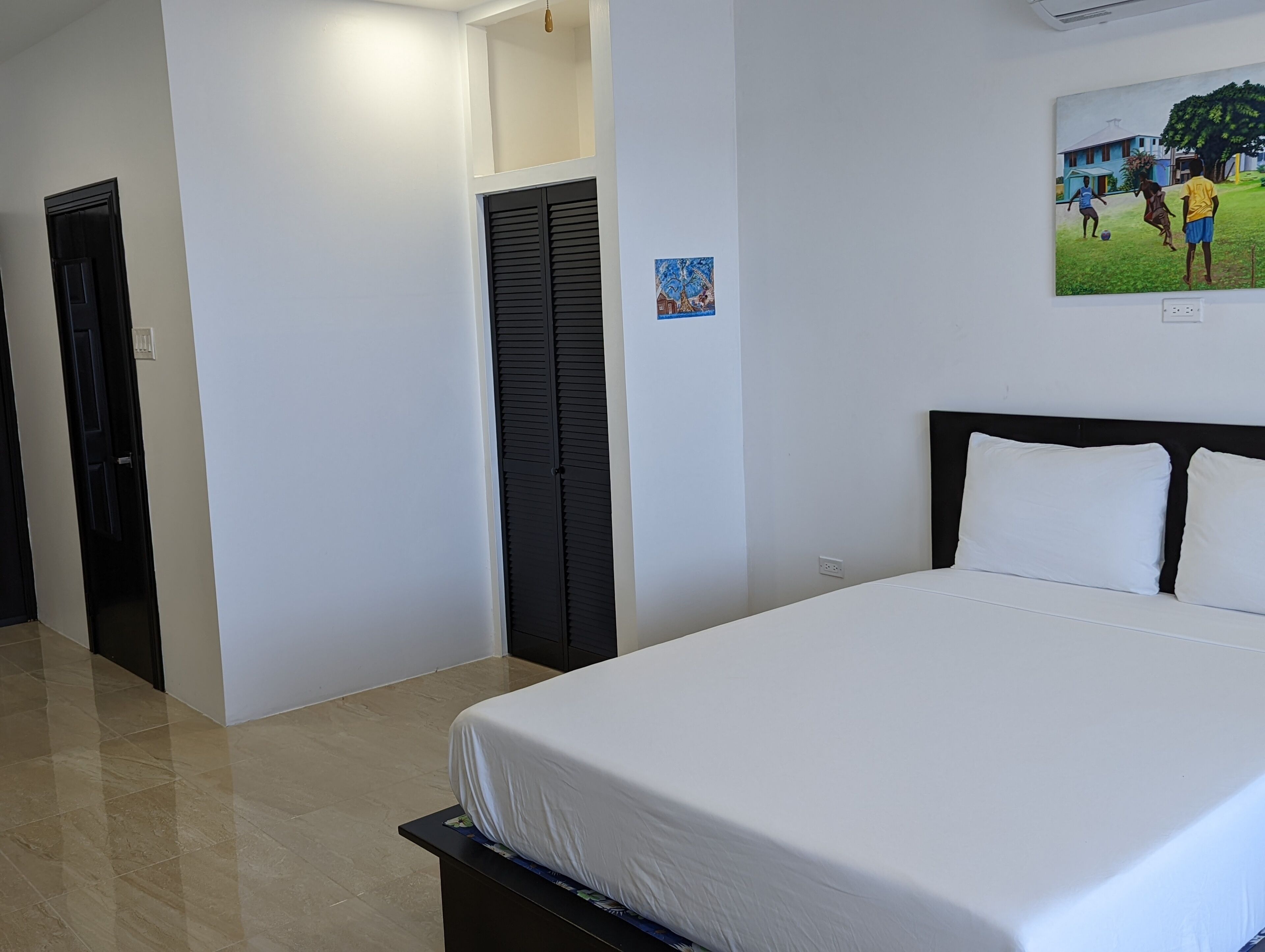 Une chambre d’hôtel avec un lit, une porte, une armoire et un tableau au mur.