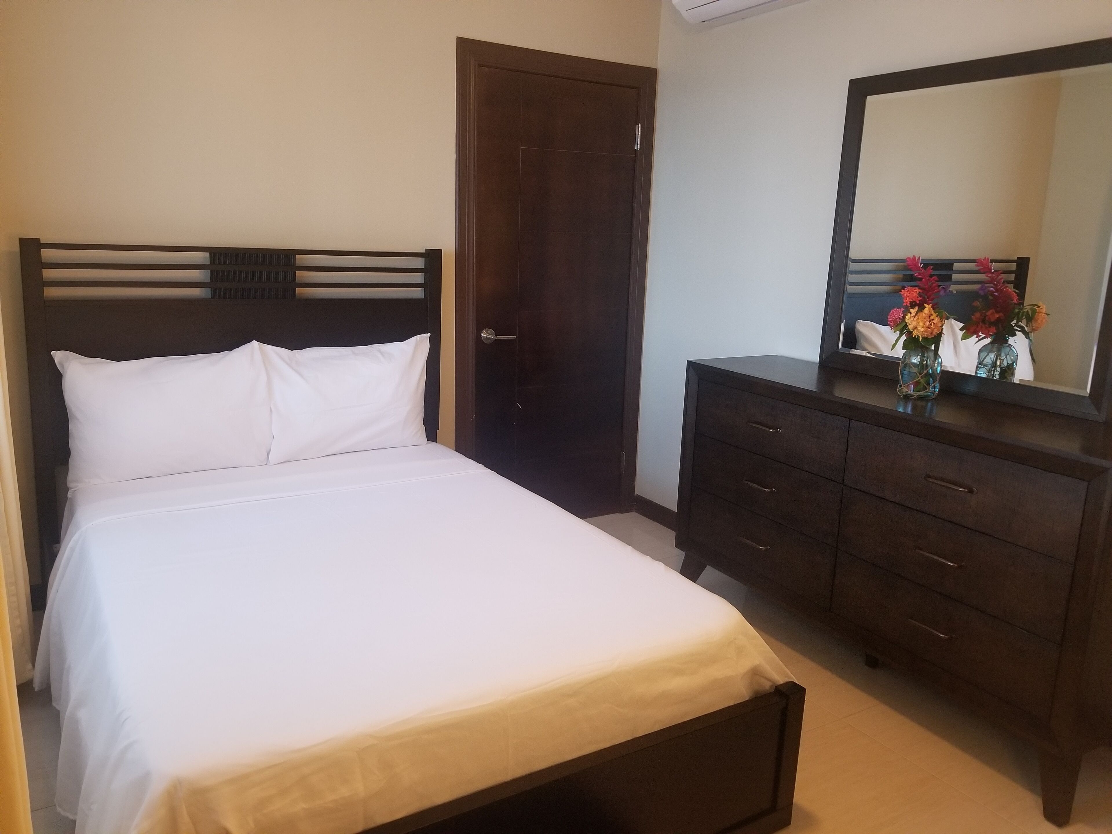 A bedroom with a bed, a dresser, and a mirror.