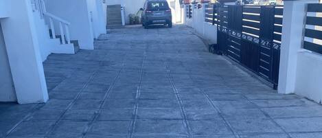 A paved driveway leading to a gated entrance with a parked car.