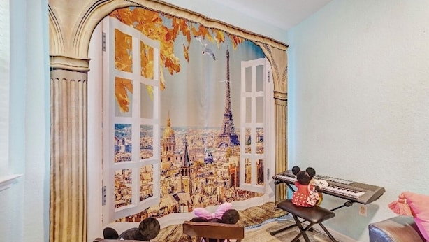 Una stanza con un grande murale che raffigura Parigi, una tastiera e morbidi peluche su una sedia.