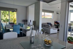 Un salón moderno con comedor, que incluye una mesa de centro de vidrio, cristalería transparente y un cuenco decorativo.