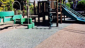 A playground with a slide, climbing structures, and green benches. - Here's to New Memories!  Luxury Condo near Disney with Resort Access! (Kissimmee)