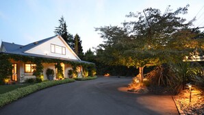 Une maison avec un toit en pente, un porche à l’avant et une allée menant à l’entrée.