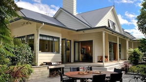 Une maison moderne dotée d’un patio couvert, de grandes fenêtres et d’une cheminée.