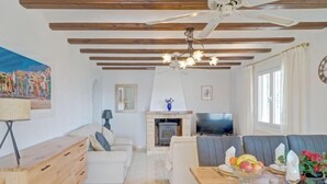 A spacious living room with a wooden ceiling, a fireplace, a television, and a dining area with a fruit bowl and table set. - La Repere by Interhome (Benissa)
