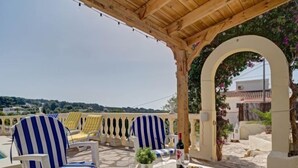 A terrace with striped chairs, a table with plates and glasses, and a view of the landscape. - La Repere by Interhome (Benissa)