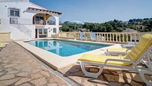 A pool area with lounge chairs, a white building with balconies, and a view of the surrounding landscape. - La Repere by Interhome (Benissa)