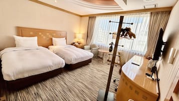 Een hotelkamer met twee bedden, een bureau, een stoel, een spiegel en een raam met gordijnen.