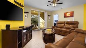 A living room with a flat-screen TV, leather sofa, and a glass coffee table. - The Mandalori-Inn - South Pool, Conservation View! (Kissimmee)
