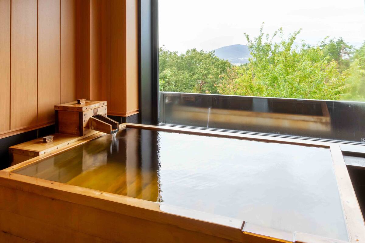 Ein traditionelles japanisches Onsen mit Holzbädern und Blick auf die grüne Landschaft.
