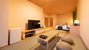 A modern hotel room with a wooden ceiling, a flat-screen TV, a bed with a white comforter, a desk with a computer, and tatami flooring. - Sekaiisannokakureyado Kajitsunomori (Ichinoseki)
