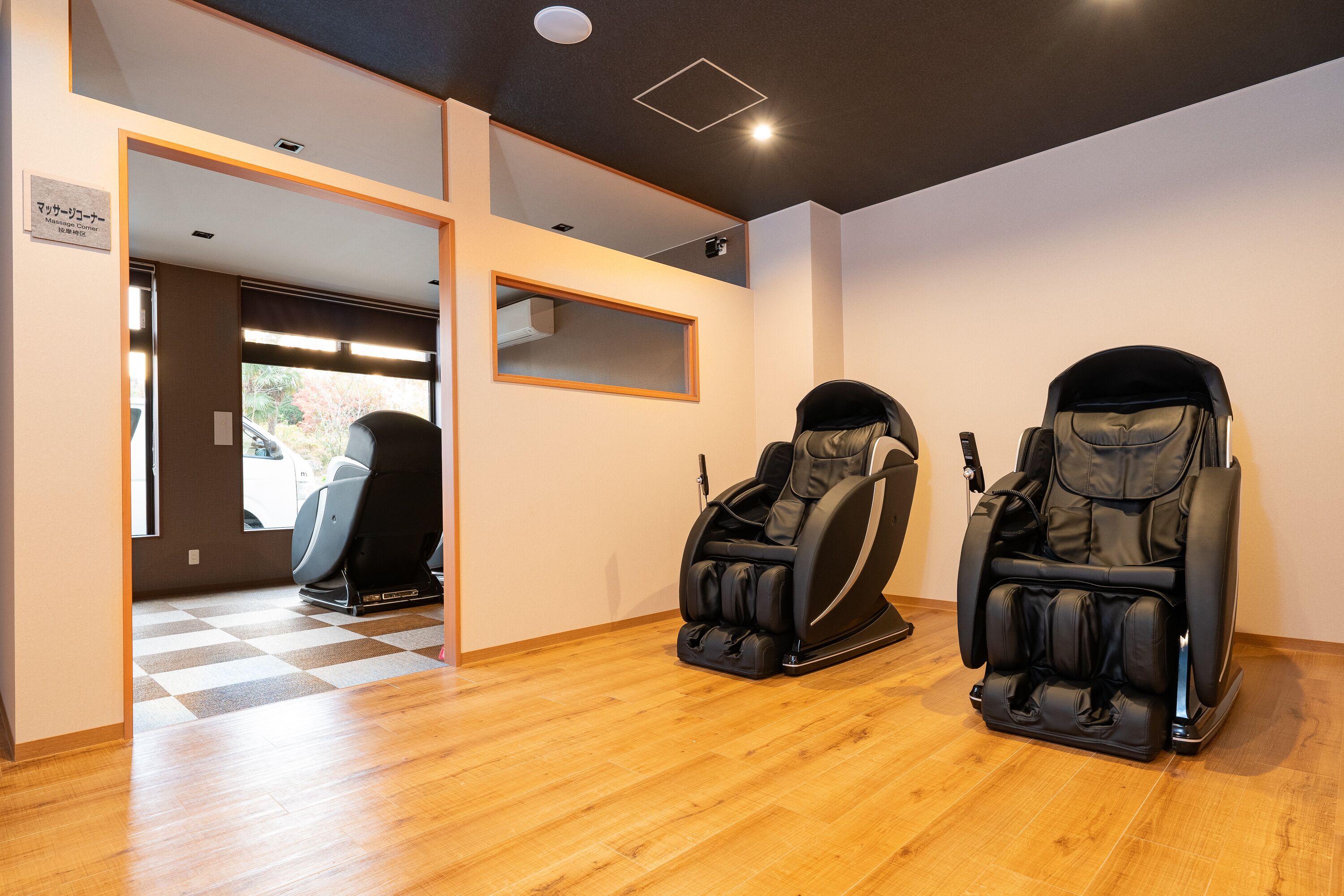 A room with two massage chairs, a checkered floor, and a sign indicating a massage room.